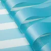 A close-up view of a blue and white striped roller blind, showing the texture and layering of the fabric. Produktbild-Vorschau