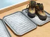 Two shoe drying trays are shown on a carpeted floor, with one tray holding a pair of hiking boots. Produktbild-Vorschau