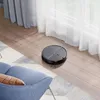 A robot vacuum cleaner is cleaning a wooden floor next to a blue armchair and a rug. Produktbild-Vorschau