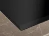 A close-up view of the corner of a black induction cooktop resting on a marble-patterned countertop. Produktbild-Vorschau