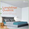 A bedroom scene with a bed made up with a petrol-colored fitted sheet and gray pillows and duvet. Produktbild-Vorschau