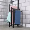 A black metal towel rack with several towels hanging on it, placed in a bathroom with tiled walls and a concrete floor. Náhľad obrázku produktu