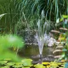 A solar-powered water fountain is operating in a pond surrounded by lush greenery and lily pads. Produktbild-Vorschau