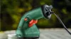 A close-up shot of a Bosch cordless shrub shear, plugged in and resting on a surface. Anteprima dell’immagine prodotto
