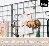 A black wire grid display with various items attached, including postcards, scissors, and a felt lion ornament. Produktbild-Vorschau