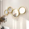 A set of four decorative gold mirrors with abstract wire frames mounted on a white wall, with dried flowers in the foreground. Produktbild-Vorschau