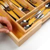 A hand is shown reaching into a wooden cutlery organizer in a drawer, with various utensils inside. Náhľad obrázku produktu