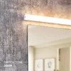 A close-up of a modern LED light fixture mounted above a mirror, reflecting a room. Produktbild-Vorschau