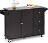 A dark brown kitchen cart with a stainless steel top is shown against a white background. It has two cabinet doors, three drawers, and a pull-out drawer on the side. A decanter, a wine glass, and a bowl of fruit are on the countertop. Podgląd zdjęcia produktu