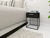 A black bedside table with a drawer next to a bed. Voir les images du produit