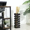 A black metal umbrella stand with rolled-up documents inside, placed next to a desk with a printer and books, and a plant in the foreground. Anteprima dell’immagine prodotto