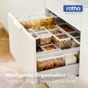 An open kitchen drawer filled with clear plastic food storage containers holding various dry goods like pasta, nuts, and grains. Produktbild-Vorschau