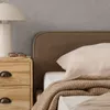 A close-up view of a bed with a nightstand and a lamp. Produktbild-Vorschau