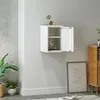 A white metal wall cabinet is mounted on a light gray wall, with a framed picture and a wooden cabinet visible in the background. Produktbild-Vorschau