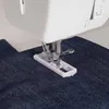 A close-up shot of a sewing machine needle and buttonhole foot working on dark blue denim fabric. Náhled obrázku produktu