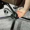 A hand is shown adjusting the height lever of an office chair. Voir les images du produit