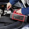 A person is using a car battery charger in the engine bay of a car. Produktbild-Vorschau