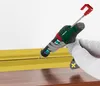 A person wearing gloves is using a cordless caulking gun to apply sealant along a yellow trim piece. Produktbild-Vorschau