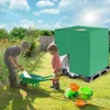 Two children playing in a garden with a hose and a toy wheelbarrow next to a large green tarp-covered object. Produktbild-Vorschau