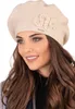 A woman wearing a beige beret with floral embellishments. Náhled obrázku produktu