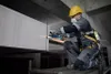 A construction worker is using an angle grinder on a concrete beam. Náhľad obrázku produktu