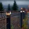 A black wire fence with solar-powered lights on top of the posts, illuminated at dusk. Anteprima dell’immagine prodotto