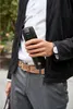 A person holding a black thermos in an outdoor setting. Podgląd zdjęcia produktu
