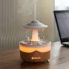 A UFO-shaped humidifier with a light and water droplets is placed on a wooden desk next to a laptop. Produktbild-Vorschau