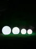 Four illuminated spherical garden lights of varying sizes are arranged in a line on a grassy lawn at night. Anteprima dell’immagine prodotto
