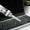 A handheld vacuum cleaner is being used to clean debris from a laptop keyboard. Produktbild-Vorschau