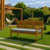 A wooden garden bench with a gray cushion sits on a green lawn, with a hammock and pergola in the background. Produktbild-Vorschau