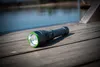 A flashlight rests on a wooden dock next to a body of water. Produktbild-Vorschau