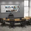 A modern conference room with a large screen displaying a video conference, a curved table, and chairs. Podgląd zdjęcia produktu