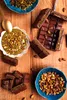 A top-down view of chocolate bars and pistachios arranged on a wooden surface. Podgląd zdjęcia produktu