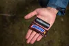 A hand holding a small black pump and a Snickers candy bar. Podgląd zdjęcia produktu