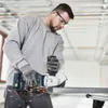 A man is using an angle grinder to cut a metal pipe in a construction environment. Produktbild-Vorschau