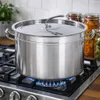 A large stainless steel pot is on a gas stove with a blue flame. Jars of preserved food are in the background. Produktbild-Vorschau