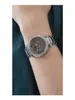 A close-up shot of a woman's arm wearing a silver Guess watch. Náhled obrázku produktu