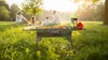 A family is having a picnic in a park with a grill in the foreground. Produktbild-Vorschau