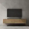 A modern, wall-mounted TV stand with a dark screen television and a soundbar, against a concrete wall. Produktbild-Vorschau