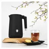 A black electric kettle is displayed on a wooden board next to a glass mug of tea and a lemon slice. Náhľad obrázku produktu