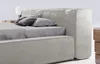 A close-up view of a modern upholstered bed with pillows and a bedside table. Náhled obrázku produktu