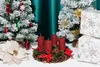 A Christmas-themed display with two flocked artificial Christmas trees, an advent wreath with red candles, decorative poinsettia, and wrapped gifts. Náhled obrázku produktu