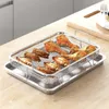 A stainless steel grill basket filled with cooked chicken wings and drumsticks sits on top of a baking tray, placed on a wooden countertop. Anteprima dell’immagine prodotto