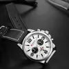 A close-up shot of a men's wristwatch with a black leather strap and a white dial, set against a dark, reflective surface. Produktbild-Vorschau