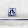 A close-up of a white textile product with a brand label attached. Produktbild-Vorschau