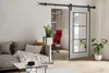 A modern living room with a sliding barn door leading to an office space. Produktbild-Vorschau