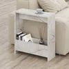 A marble-effect side table with books and a diffuser next to a sofa. Produktbild-Vorschau