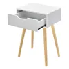 A white bedside table with a drawer partially open, supported by three wooden legs. Náhled obrázku produktu