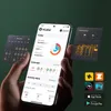 A hand holding a smartphone displaying a fitness app, with other app interfaces floating around it. Produktbild-Vorschau